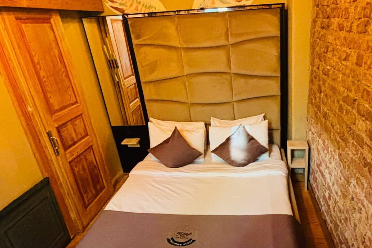 A bed with a headboard, pillows, and a logo on the bedspread.