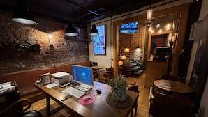 Un restaurante acogedor con pared de ladrillo rústico, mesas de madera y luces colgantes.