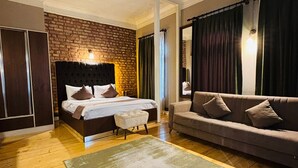 Un dormitorio con pared de ladrillo, una cama con cabecero, un sofá y un tapete grande.