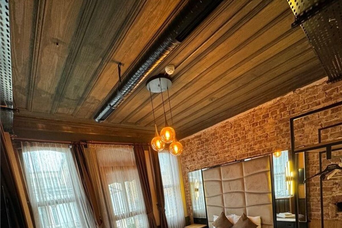 Een slaapkamer met een groot bed, houten vloeren, een bakstenen muur en een bureau met een stoel.
