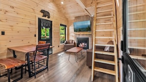 A wooden cabin interior with a fireplace, a television, and a dining area. - TreeLodge, Downtown Pigeon Forge (Pigeon Forge)