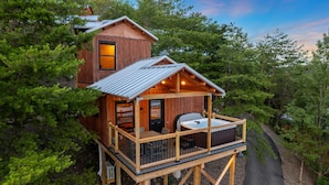 A wooden cabin with a balcony and hot tub, surrounded by trees. - TreeLodge, Downtown Pigeon Forge (Pigeon Forge)