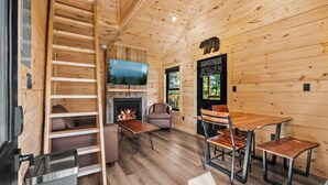 A log cabin interior with a fireplace, a television, a sofa, and a dining table. - TreeLodge, Downtown Pigeon Forge (Pigeon Forge)