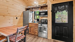A compact kitchen with a wooden interior, a dining table, and a black door. - TreeLodge, Downtown Pigeon Forge (Pigeon Forge)