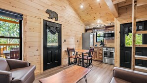 A wooden cabin interior with a dining area, kitchen, and a black bear decoration on the wall. - #5 Mt LeConte Little Forge Resort Pigeon Forge (Pigeon Forge)