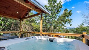 Un bain à remous avec une terrasse en bois et une vue sur les arbres et les montagnes.