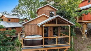 A wooden cabin with a hot tub, deck, and a small attached structure. - TreeLodge, Downtown Pigeon Forge (Pigeon Forge)