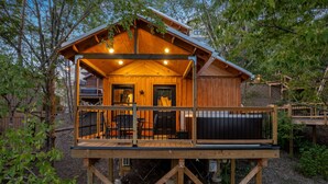 A wooden cabin with a balcony, a door, and a window.