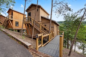 A wooden cabin with a staircase leading to a deck, surrounded by trees and a lake view. - TreeLodge, Downtown Pigeon Forge (Pigeon Forge)