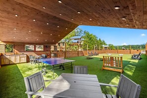 An outdoor area with a ping pong table, seating, and a wooden deck. - Little Forge TreeLodge, Downtown Pigeon Forge (Pigeon Forge)