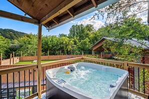 Un bain à remous sur une terrasse en bois, avec vue sur une zone boisée.