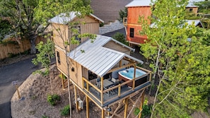 Une terrasse en bois avec un jacuzzi, entourée d’arbres et d’un mur de briques.
