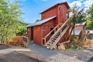 A red wooden building with a staircase leading to a deck.