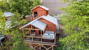 En træhytte med jacuzzi, terrasse og et lille tårn.