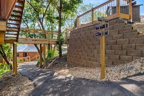 A wooden staircase leading to a building with a brick wall and a sign indicating the Tree Lodge trail.