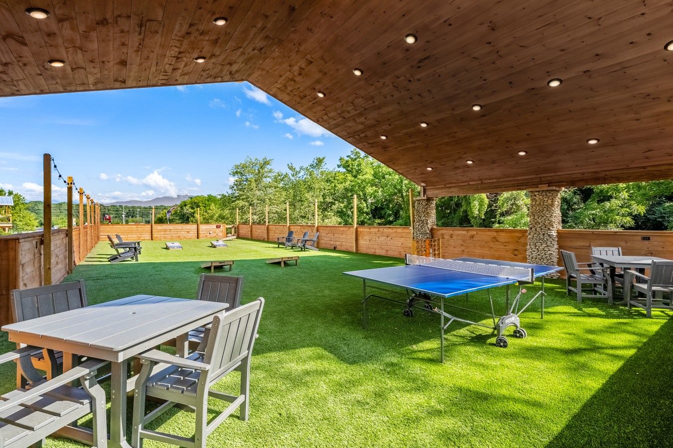 Eine Terrasse im Freien mit einem Tischtennisschläger, Sitzgelegenheiten und einem Holzboden.