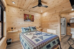 A wooden cabin bedroom with a bed, a ceiling fan, a painting, a sink, and a shower. - TreeLodge, Downtown Pigeon Forge (Pigeon Forge)