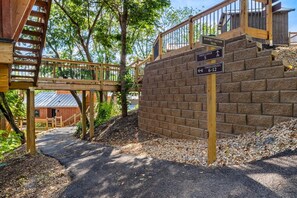 A wooden staircase leading to a building with a brick wall and a sign indicating the Tree Lodge trail. - TreeLodge, Downtown Pigeon Forge (Pigeon Forge)