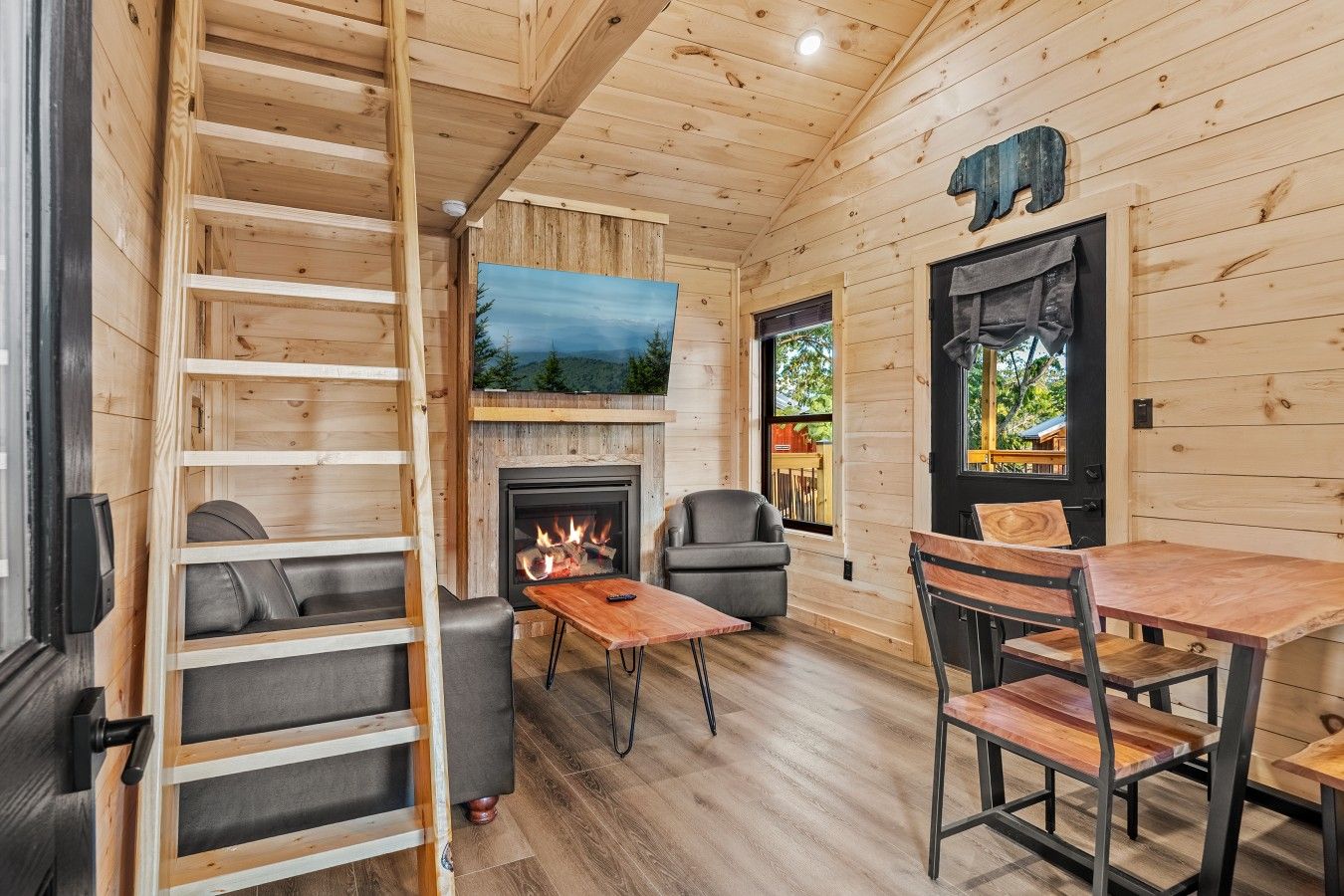 A cozy cabin interior with a fireplace, seating area, and a television.