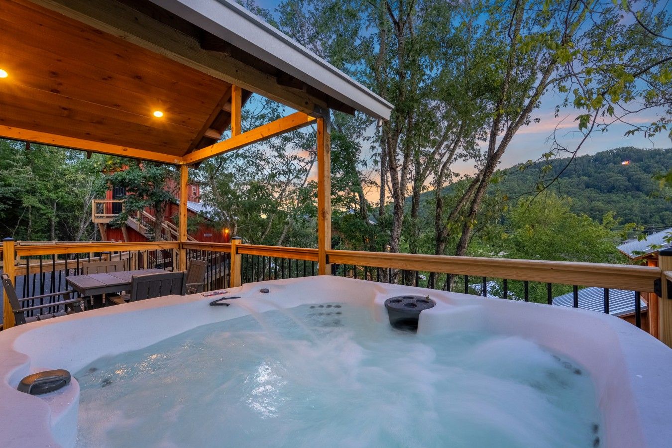 A hot tub on a wooden deck with a view of trees and hills.