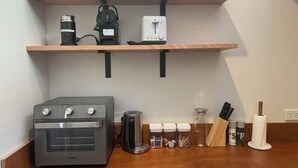 A kitchen with a built-in oven, a coffee maker, a toaster, and various kitchen utensils on the counter. - Urban Nook Serviced Apartments (Launceston)
