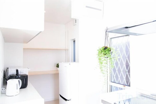 A modern kitchen with a kettle, a coffee maker, and a refrigerator. - Shizukinosato Tsuki Terrace 531 (Awaji)