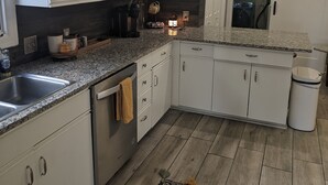 Une cuisine moderne avec des armoires blanches, des comptoirs en granit et un plancher en bois.