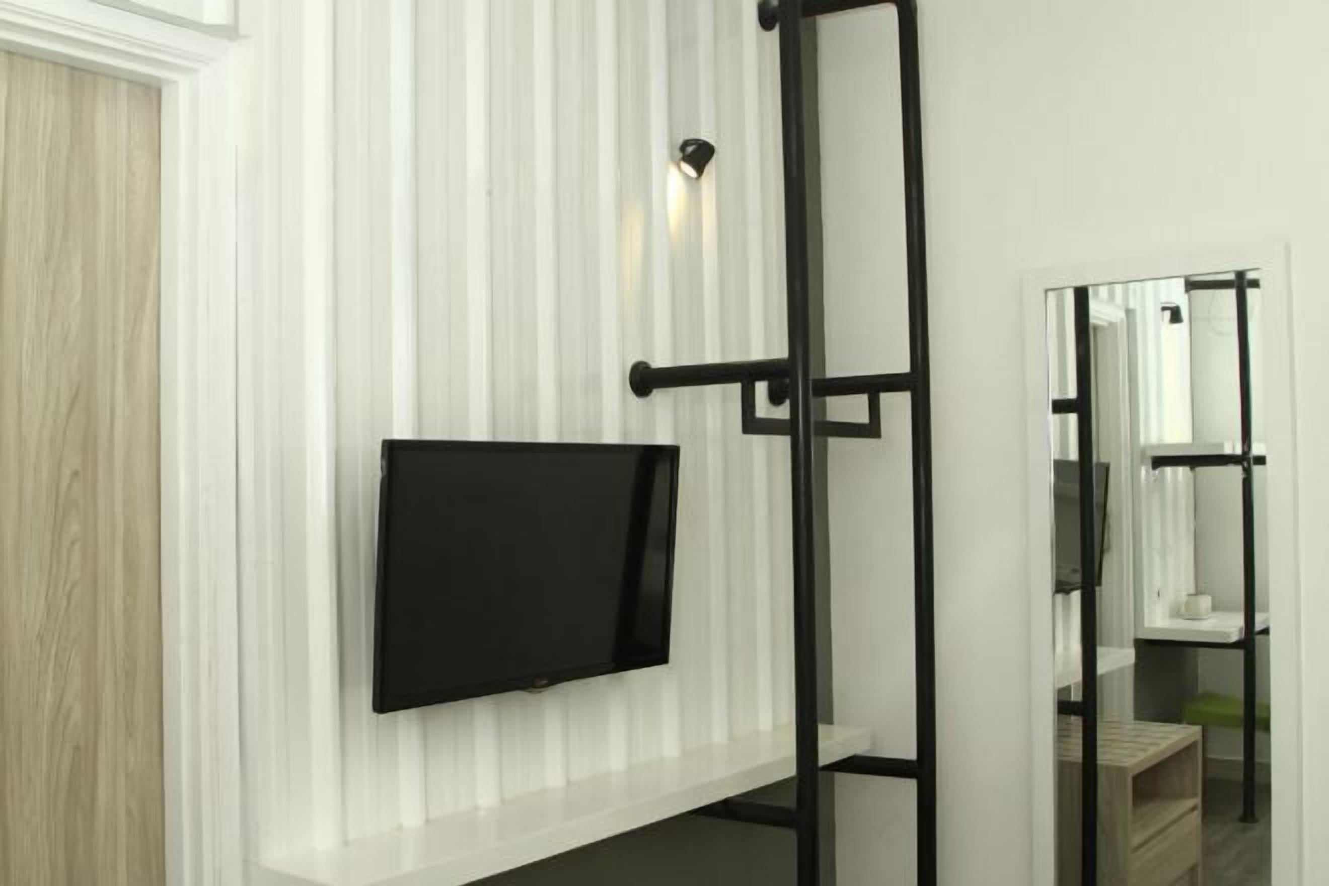 A room with a mounted television, a mirror, and a black metal ladder.