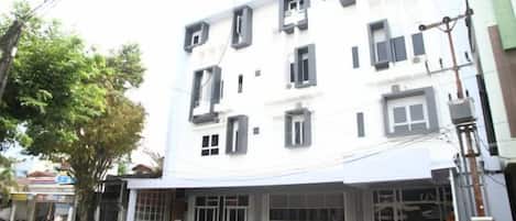Un edificio de varios pisos con fachada blanca y numerosas ventanas.