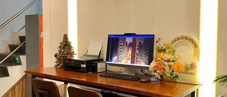 A wooden desk with a computer, two chairs, a small Christmas tree, and a decorative plate.