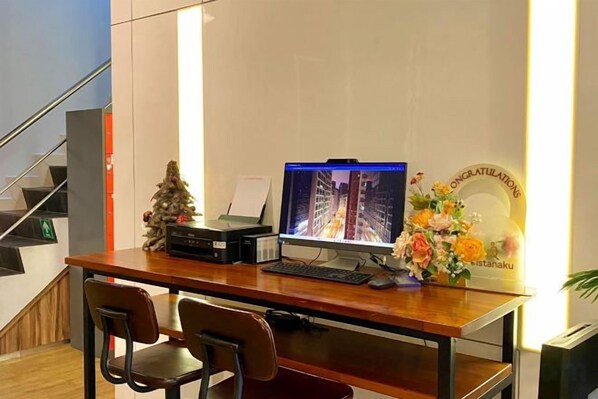 A wooden desk with a computer, two chairs, a small Christmas tree, and a decorative plate. - Istanaku Hotel Manado (Wenang)