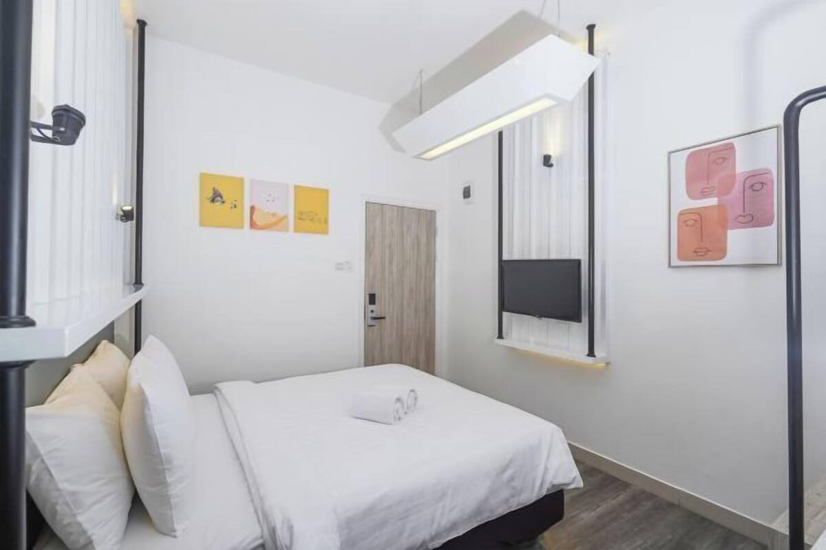 Una habitación de hotel moderna con cama, mesita de noche, espejo y obras de arte en las paredes.