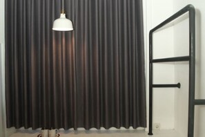 A room with a dark curtain, a white pendant light, and a black metal railing. - Istanaku Hotel Manado (Wenang)