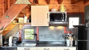 A compact kitchen with wooden cabinets, a microwave, a refrigerator, and a window with a view.