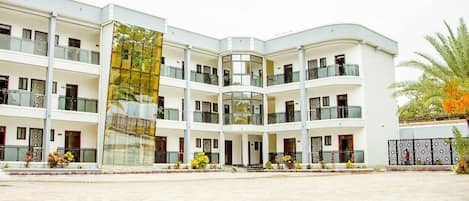 A multi-story hotel with a central courtyard, balconies, and a glass facade.