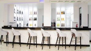 A bar area with white bar stools and shelves stocked with various bottles. - Wils Hotel SUpreme (Lusaka)