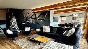 A modern living room with a wooden floor, a black sofa, a coffee table, and a Christmas tree. - Loft Eclipse 1723 (Font-Romeu-Odeillo-Via)