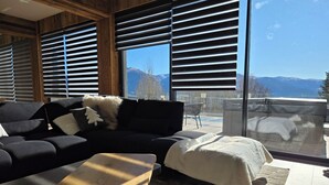 A modern living room with a sofa, a coffee table, and a view of mountains through large windows. - Loft Eclipse 1723 (Font-Romeu-Odeillo-Via)