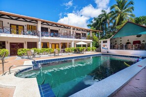 Hotel com piscina, área de estar externa e espaço coberto com mural.