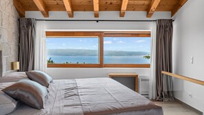 A bedroom with a large window, a bed, a bedside table, and a wooden ceiling. - Villa La Rustica with Pool (Jesenice)