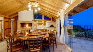 A cozy wooden interior with a dining area, fireplace, and large windows overlooking a scenic view. - Villa La Rustica with Pool (Jesenice)