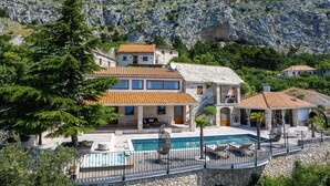 A stone villa with a swimming pool, surrounded by rocky terrain and greenery. - Villa La Rustica with Pool (Jesenice)
