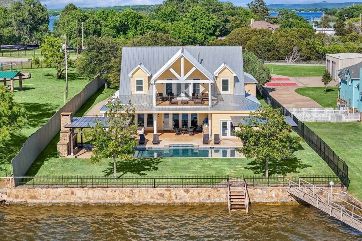 A large house with a pool, a covered patio, and a view of a body of water.