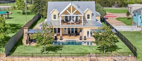 A large house with a pool, a covered patio, and a view of a body of water.