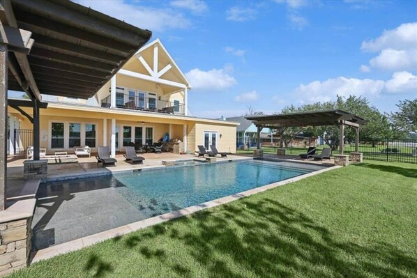A two-story house with a swimming pool, outdoor seating, and a covered patio.