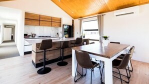 A modern kitchen with wooden cabinets, a marble countertop, and a dining area with a wooden table and chairs. - RodmanStar Apartment (Lake Tekapo)
