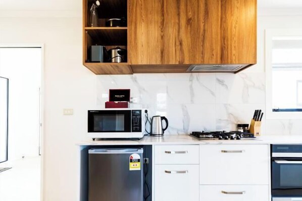 Una cocina moderna con microondas, estufa y refrigerador incorporados.