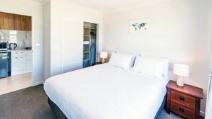 A hotel room with a bed, bedside tables, a wardrobe, and a kitchenette. - RodmanStar Apartment (Lake Tekapo)