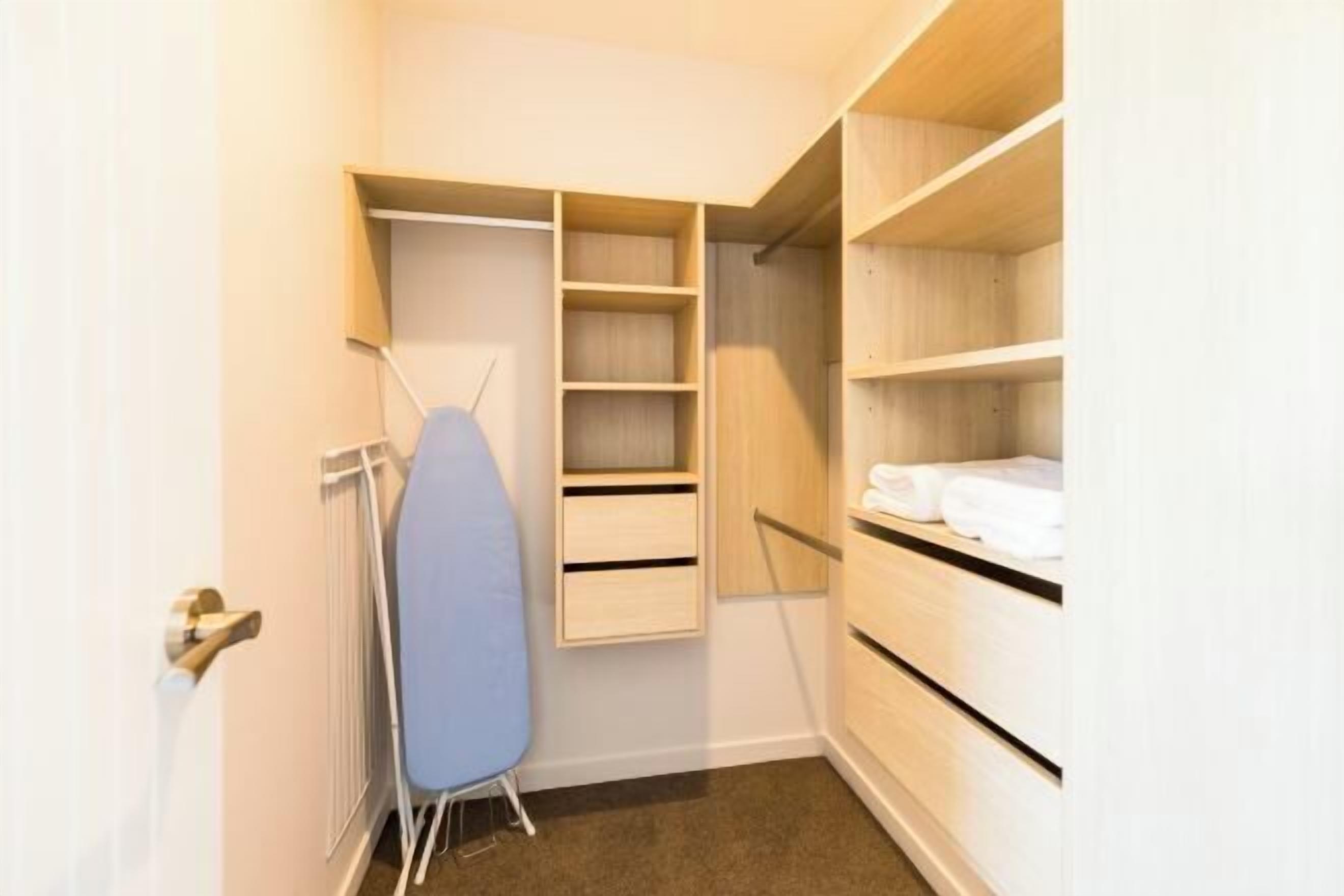 A walk-in closet with open shelving, a hanging rack, and a radiator.
