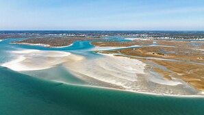 Oversigtsbillede af et kystområde med krystalklart, blåt vand, sandstrande og en by i det fjerne.